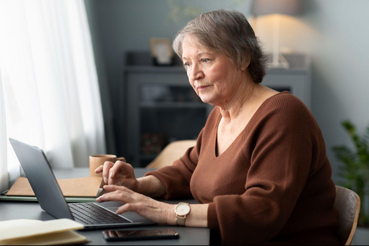 Mulher idosa mexendo no computador.&nbsp;