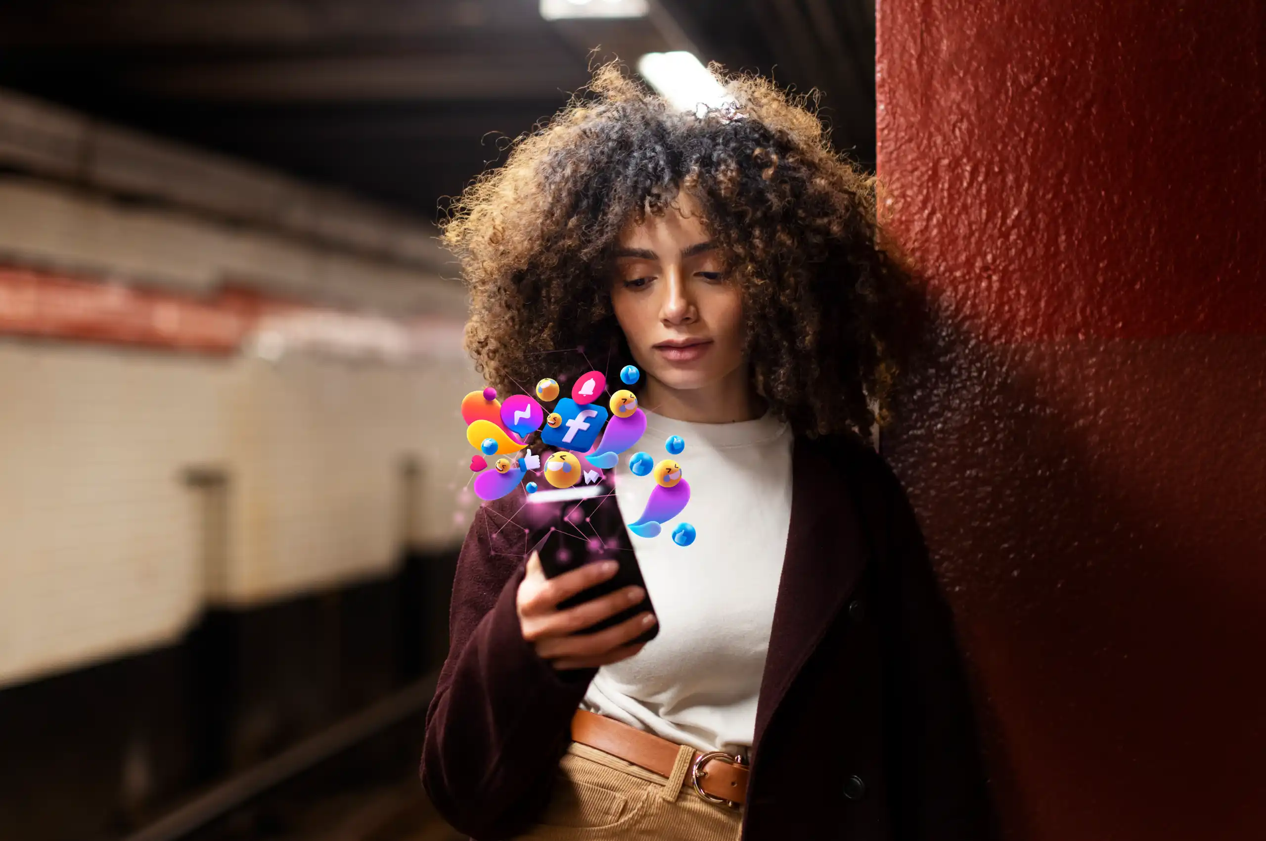 Jovem segurando um celular em uma estação de metrô, com ícones de redes sociais coloridos surgindo ao redor da tela. 