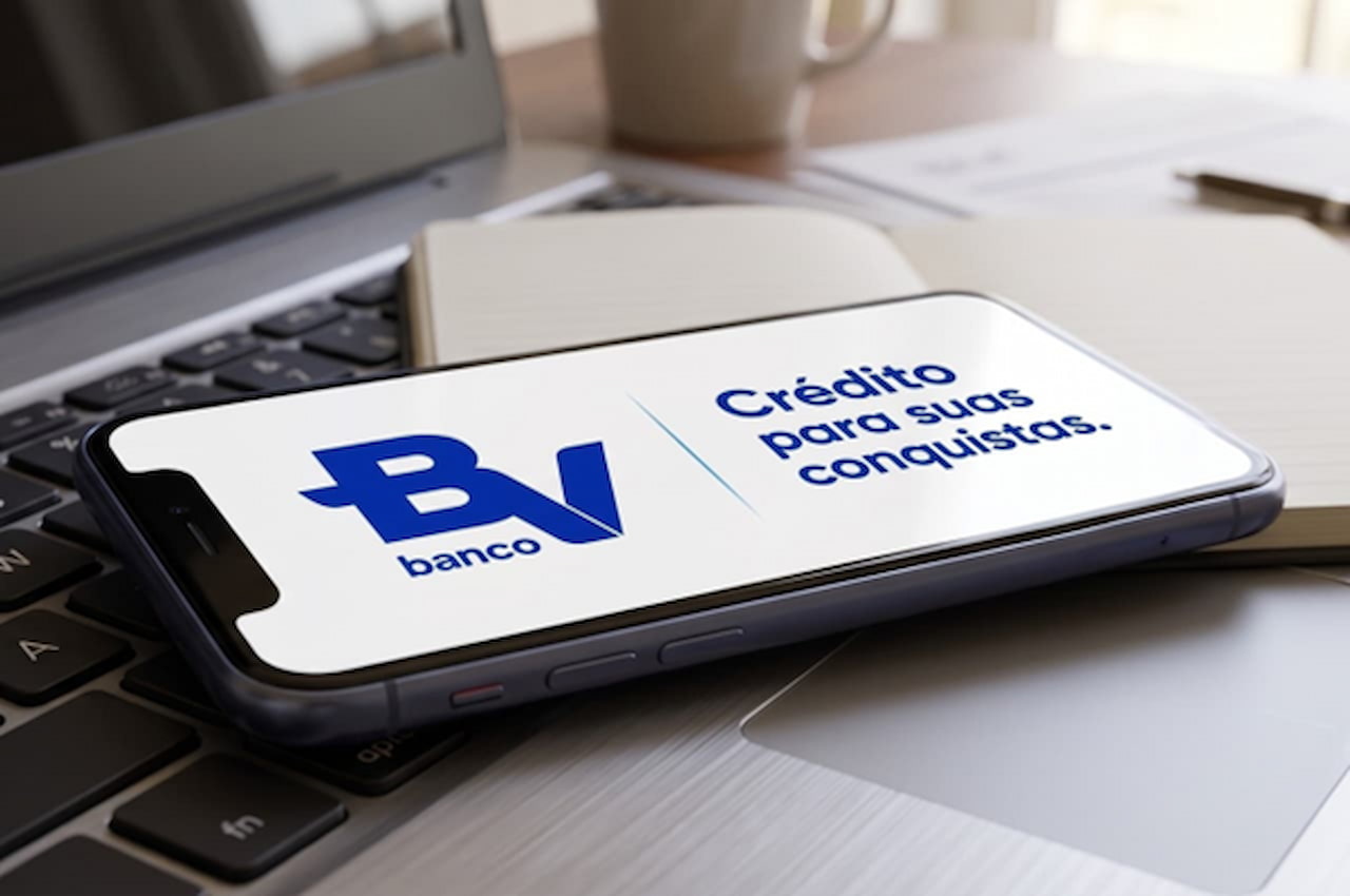 Smartphone em cima de um teclado de notebook, com o logotipo do banco BV na tela.