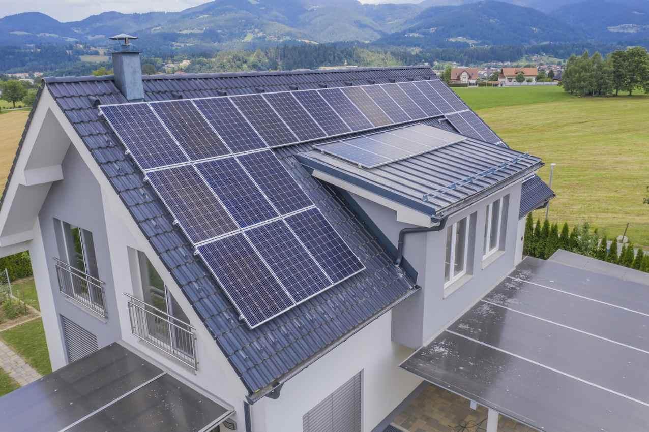 Casa com painéis solares no telhado, simbolizando a adoção de energia renovável e a redução de custos com eletricidade.