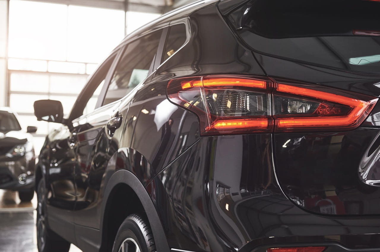 SUV preto dentro de uma concessionária, exibido sob luz natural, com destaque ao seu acabamento brilhante.