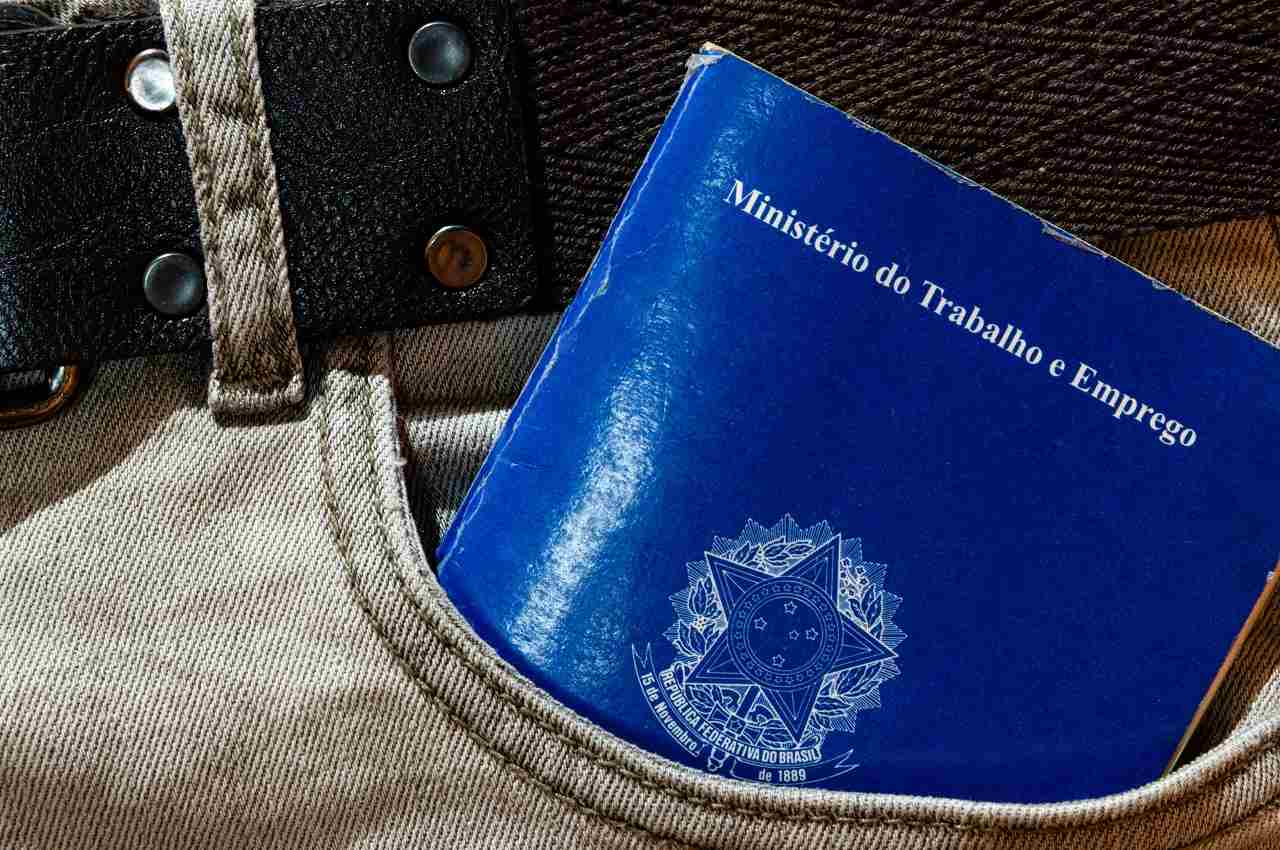 Carteira de Trabalho e Emprego (CLT) brasileira no bolso de uma calça jeans. A pessoa não aparece na imagem.