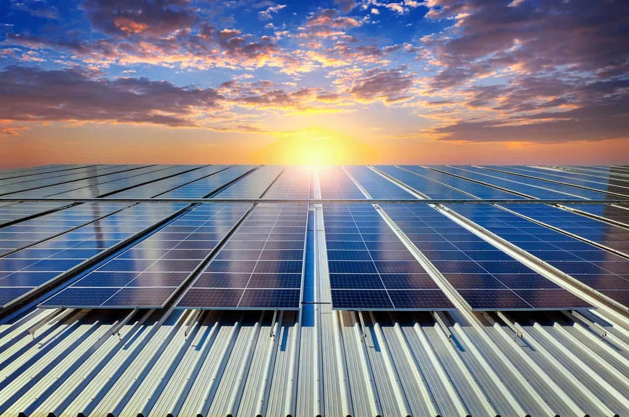 Painéis solares instalados em um telhado sob céu ao pôr do sol.