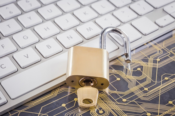 Cadeado dourado aberto com chave inserida, em cima de um teclado de laptop, simbolizando como o Open Finance é seguro.