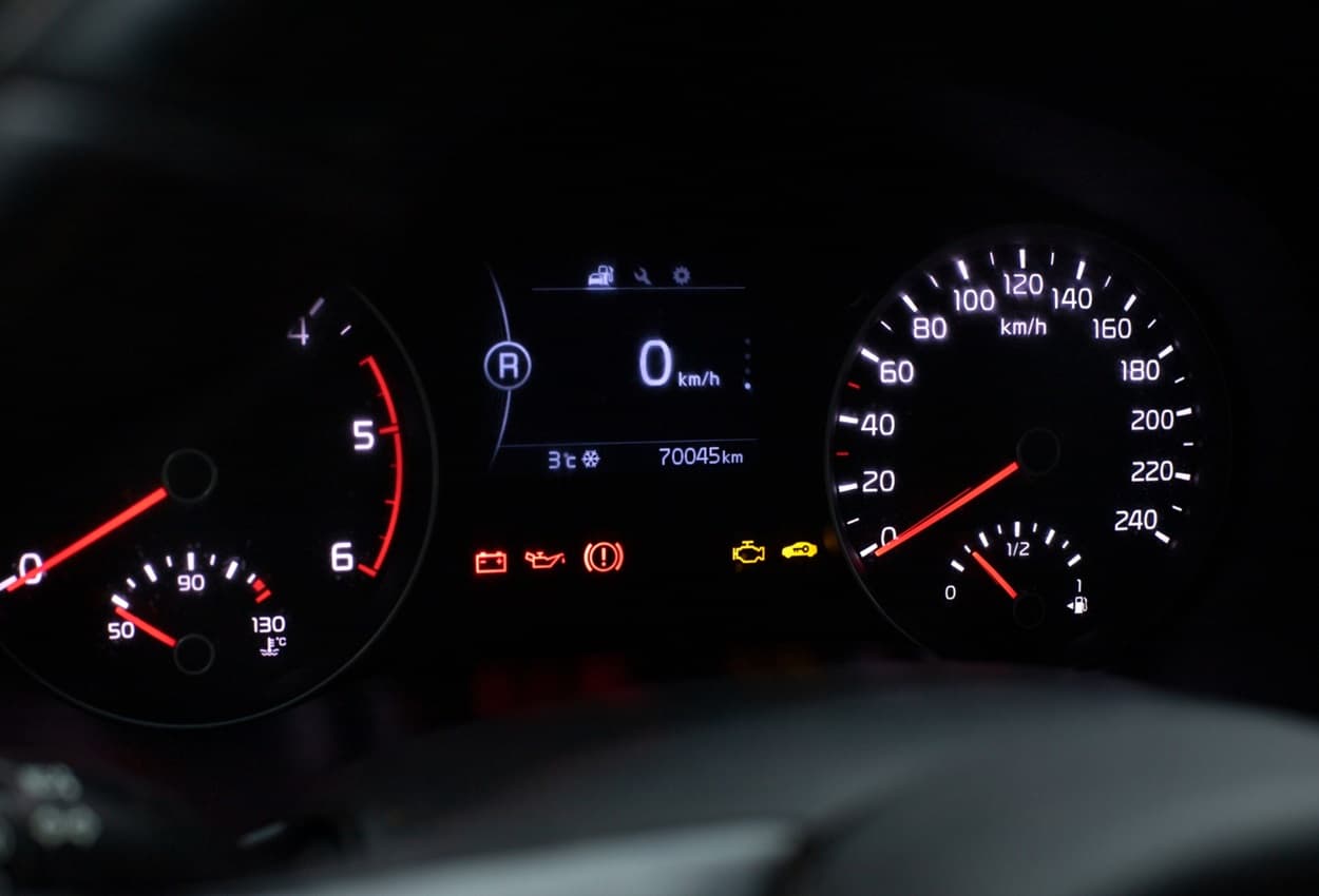 Painel de carro com múltiplas luzes acesas.