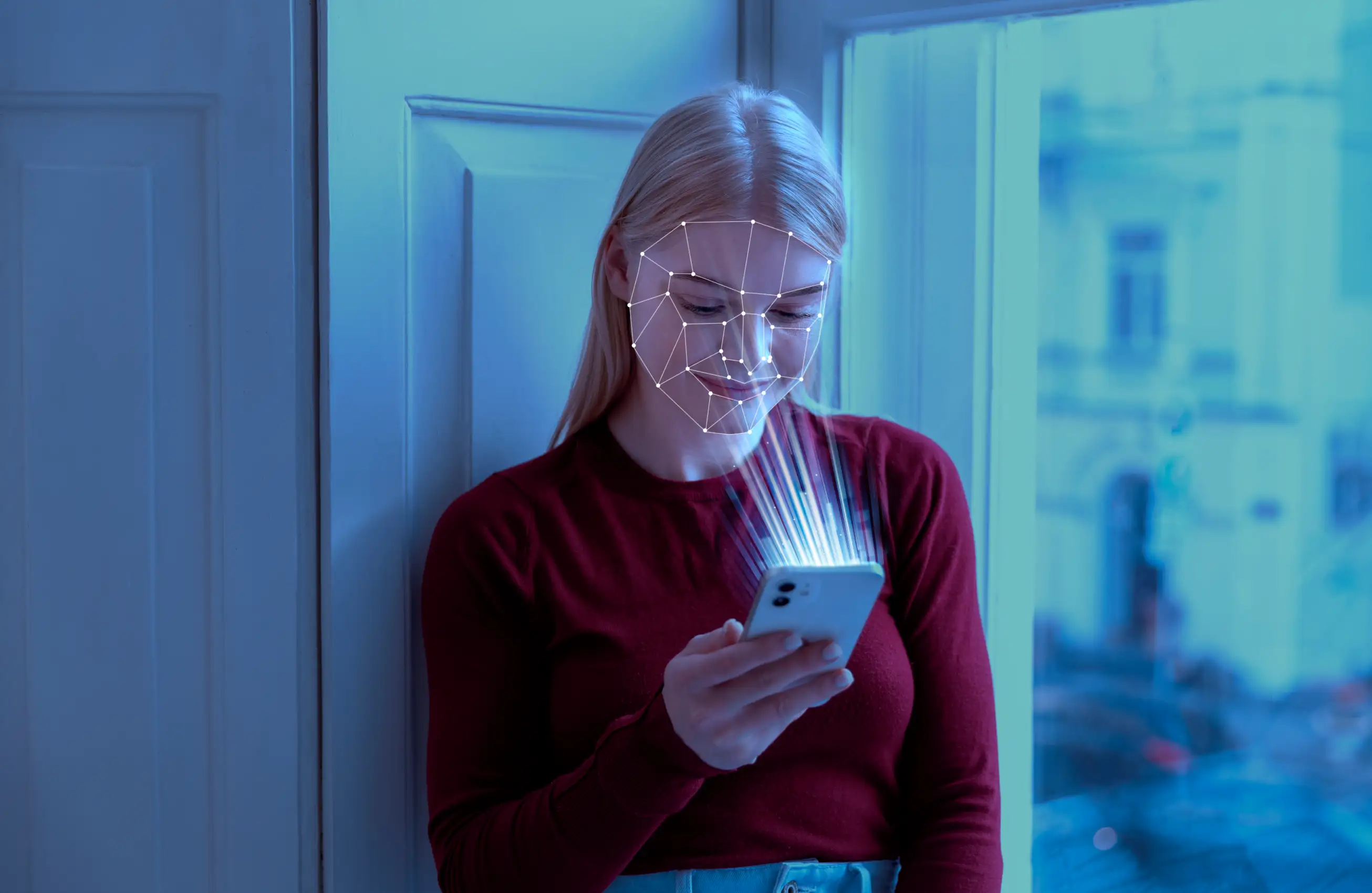 Pessoa encostada à parede segurando um smartphone; sobre o rosto há uma malha de pontos e linhas projetada digitalmente, sugerindo reconhecimento facial ou mapeamento biométrico enquanto o telefone emite feixes de luz.&nbsp;