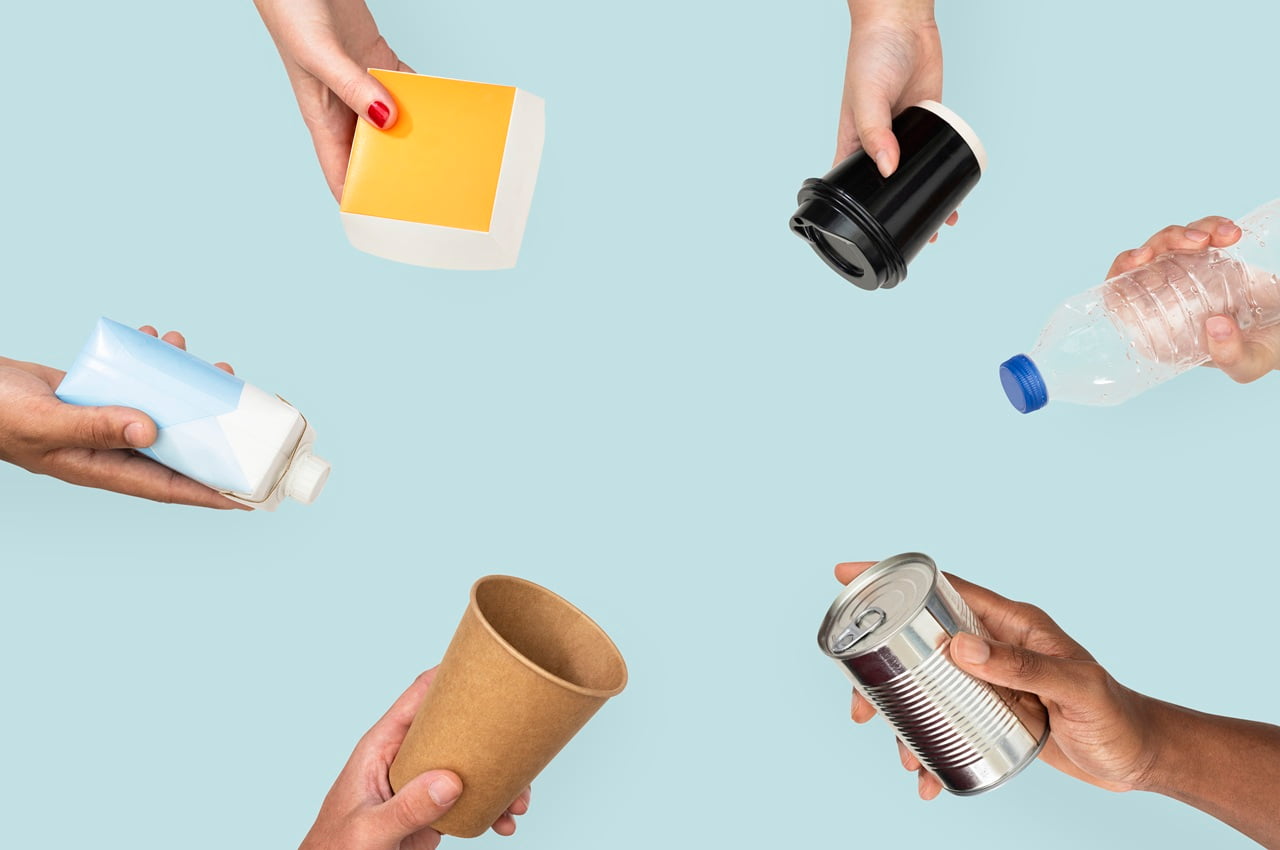 Círculo formado por mãos segurando diferentes tipos de embalagens recicláveis, simbolizando os diferentes tipos de resíduos.