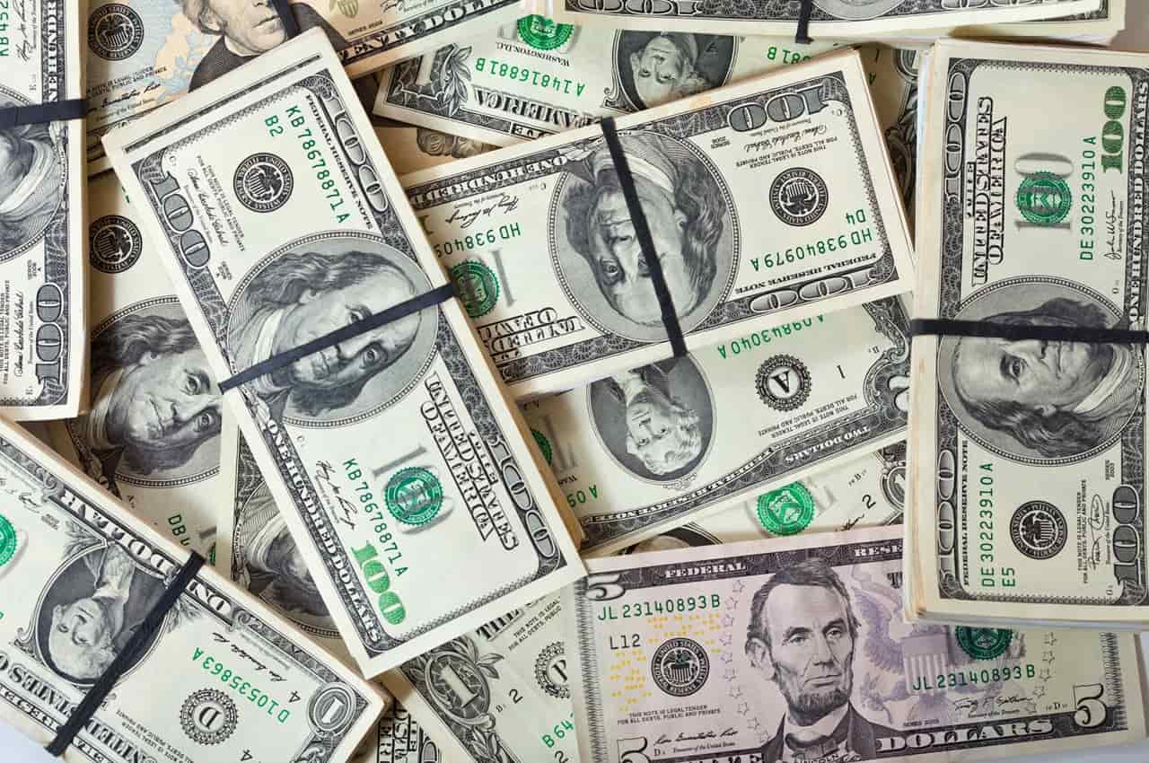 Cédulas de dólares organizadas em pilhas, simbolizando o papel dessa moeda no câmbio flutuante.