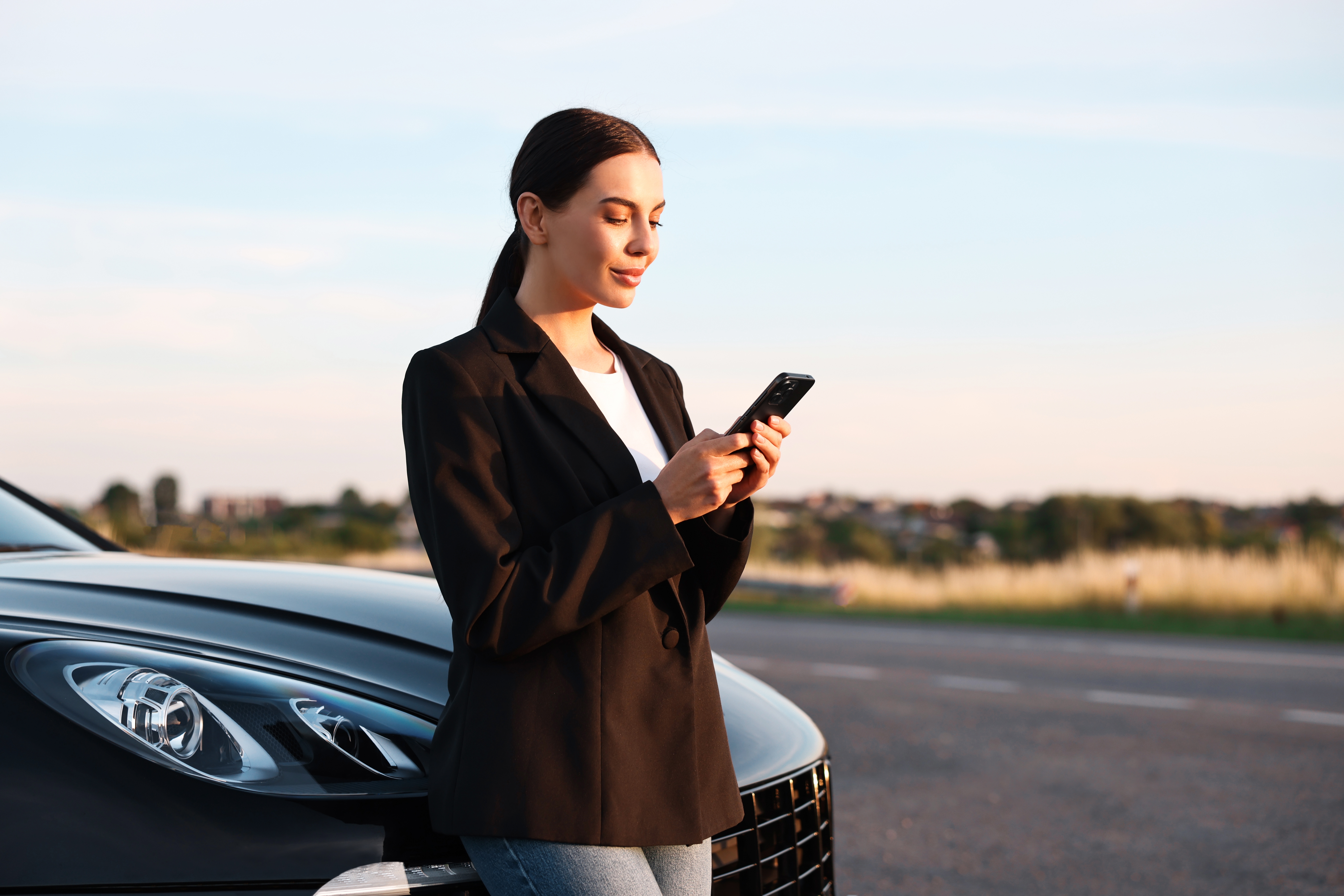 mulher encostada no carro mexendo no celular