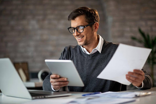 Homem sorridente organizando suas finanças, simbolizando os benefícios do Open Finance para uma gestão mais simples e eficiente do dinheiro. 