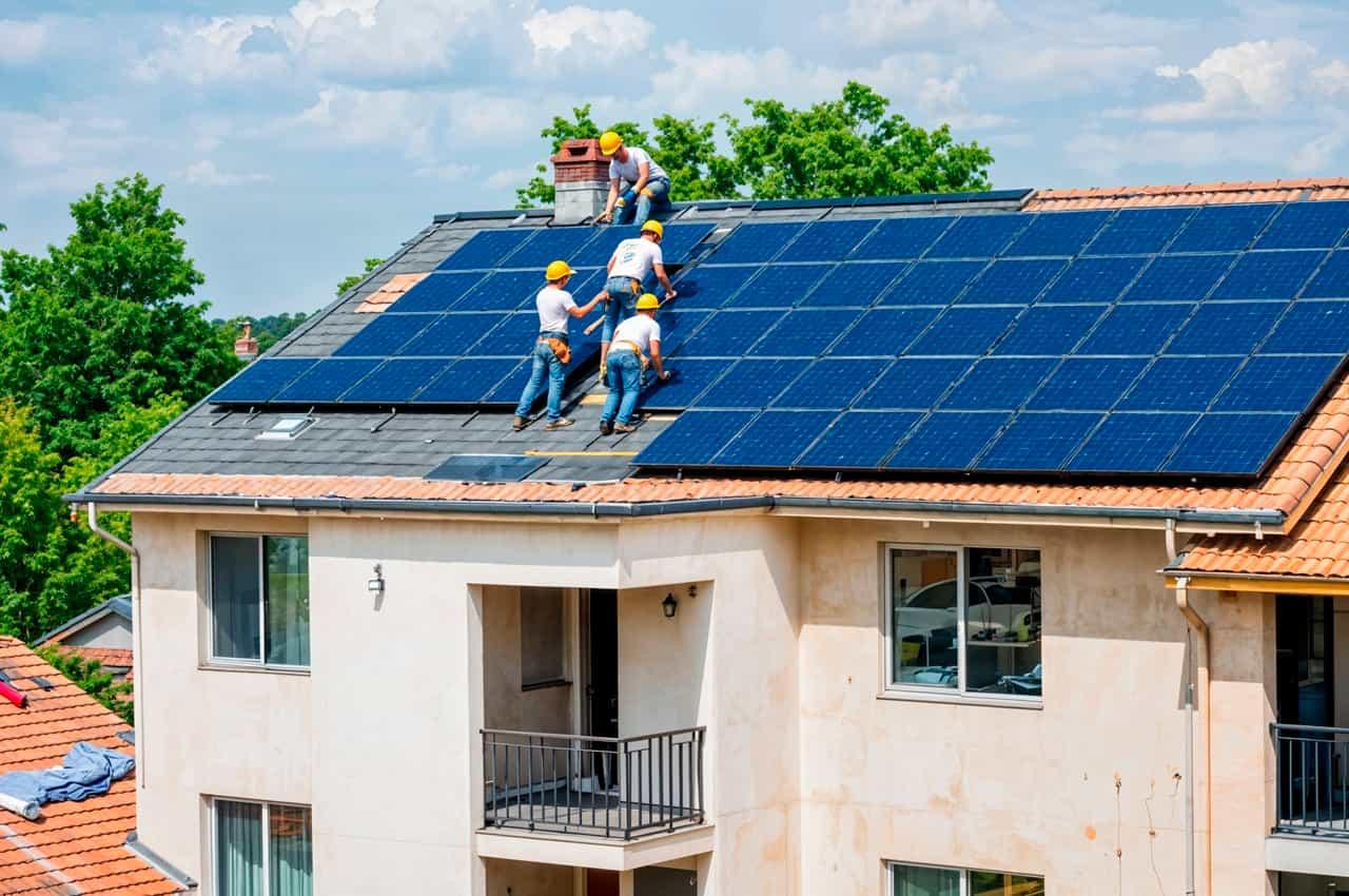 Pessoas trabalhando na instalação de placas solares para ar-condicionado no telhado de uma casa.