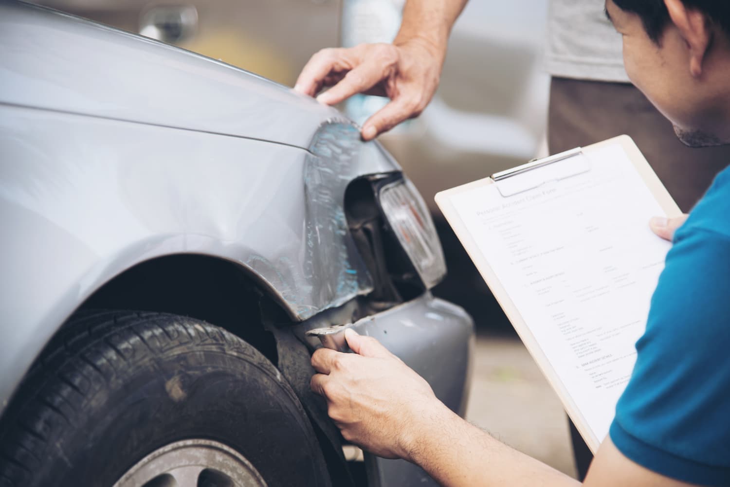Homem analisando e fazendo a inspeção da lateria de um carro batido.