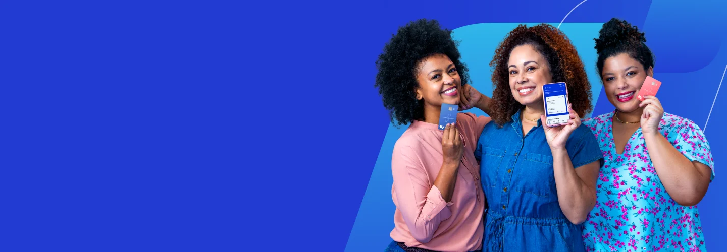 Imagem com 3 mulheres negras, de cabelos cacheados, lada a lado. A primeira delas veste uma blusa na cor rosa coral e em uma das mãos, segura o Cartão BV na cor azul. A segunda delas veste uma blusa na cor azul e segura um aparelho celular, mostrando a tela inicial da Conta BV. Já a terceira das mulheres veste uma blusa na cor azul e com estampa de flores rosas, e segura o Cartão BV na cor rosa coral.