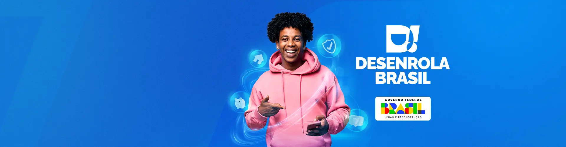 Fundo com tons de azul. No meio, está um homem negro sorrindo, de moletom rosa, com um celular na mão. Ícones de casa, cofre, curtida de coração e proteção estão ao seu redor. Do lado direito, está o logo do Desenrola Brasil e do Governo Federal.