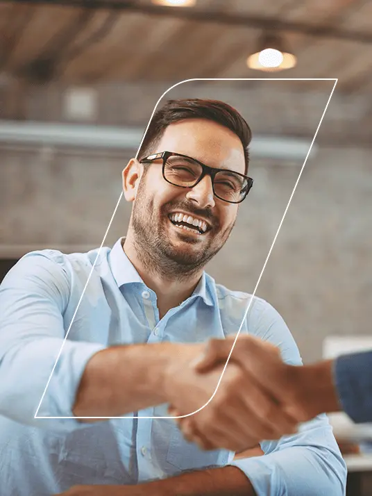 Homem sorrindo, cumprimentando outra pessoa num ambiente de trabalho