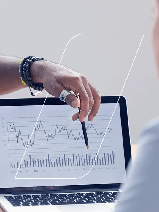 Tela de um computador portátil exibindo um gráfico, e a mão de uma pessoa apontando para ele